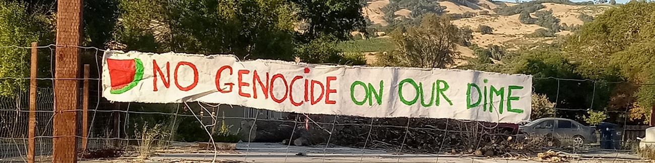 “No Genocide on Our Dime” sign hung on fence.